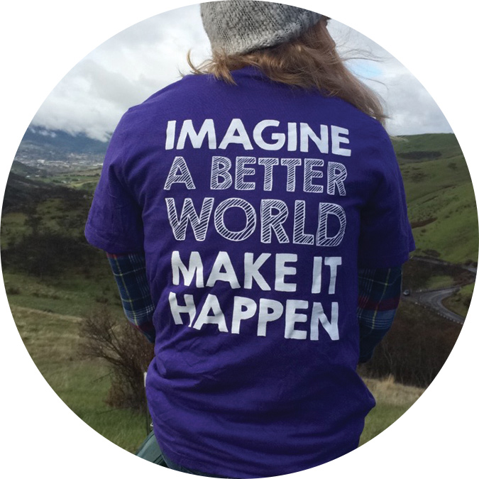 A CEL student with their back turned showing off their shirt that reads, "Imagine a better world, make it happen"